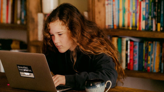 Image d'une ado regardant son ordinateur de façon interrogative 